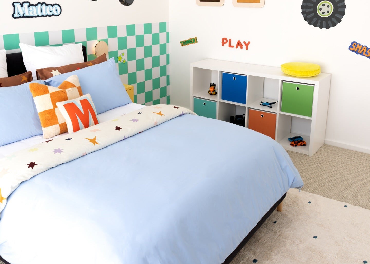 Children's bedroom with monster truck decals and colorful furniture.
