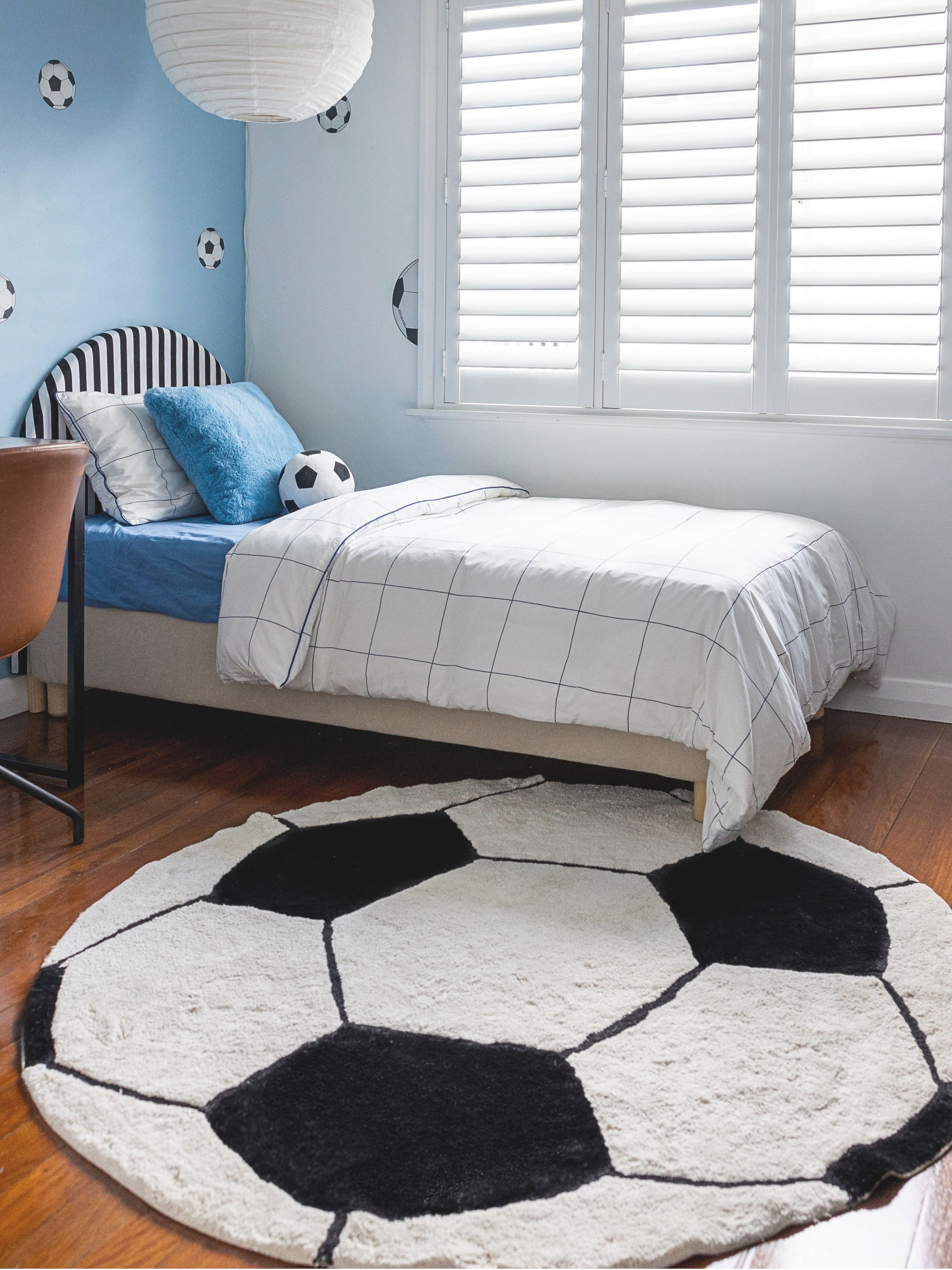Children's bedroom with a soccer ball rug and bed.