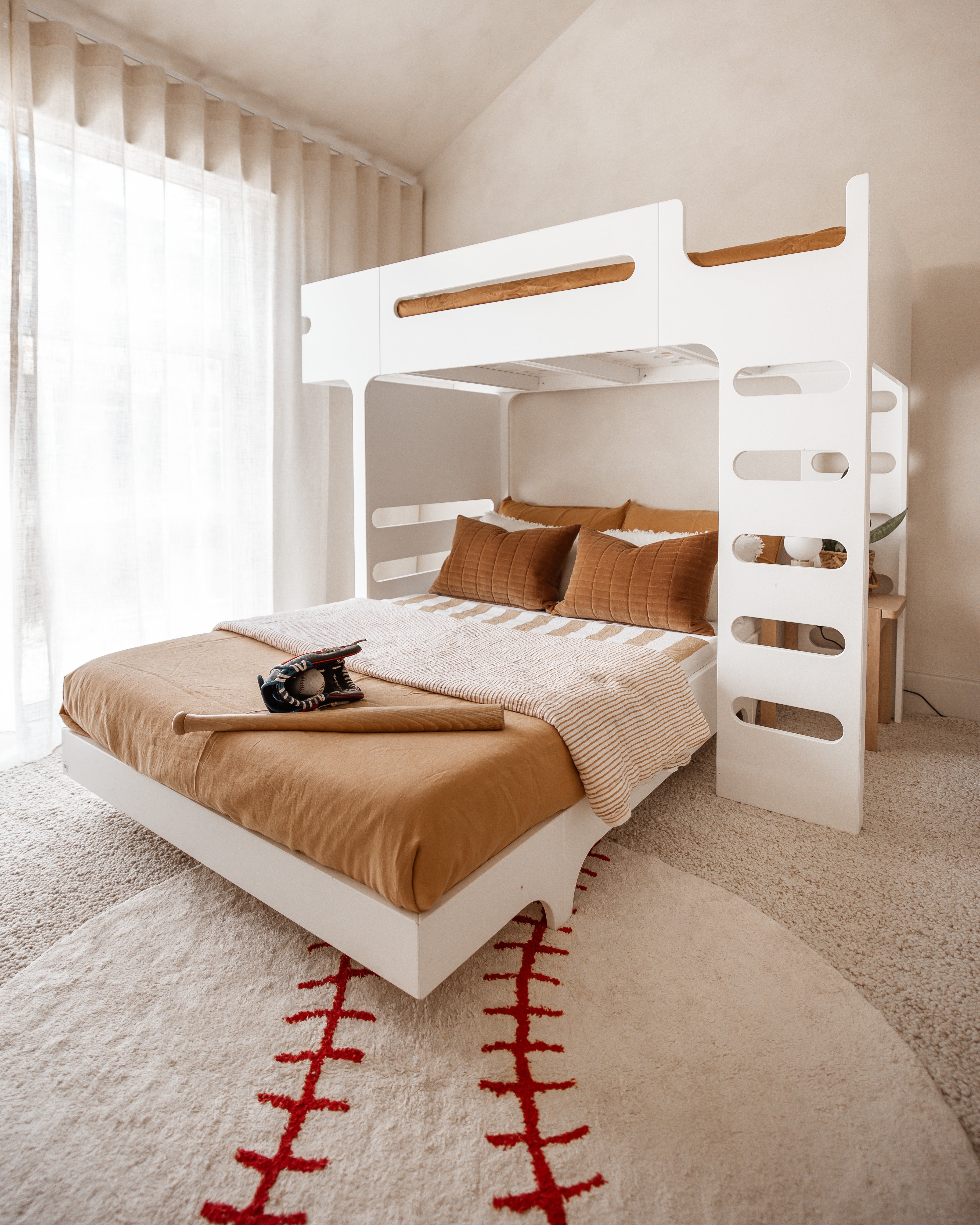 White bunk bed with brown bedding in a room with light-colored walls and a rug.