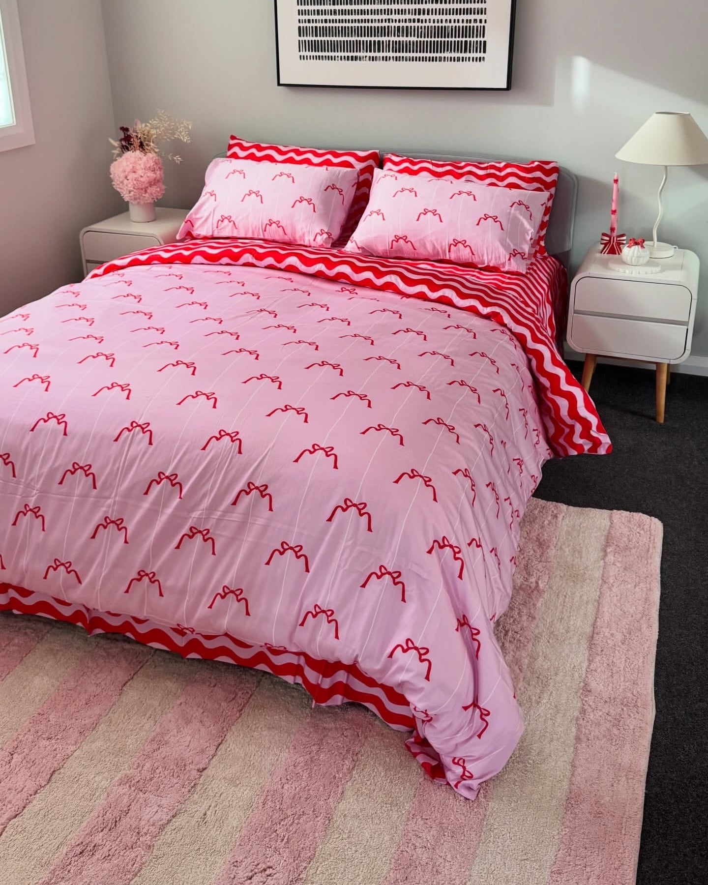Pink and red patterned bedding set on a bed in a bedroom.
