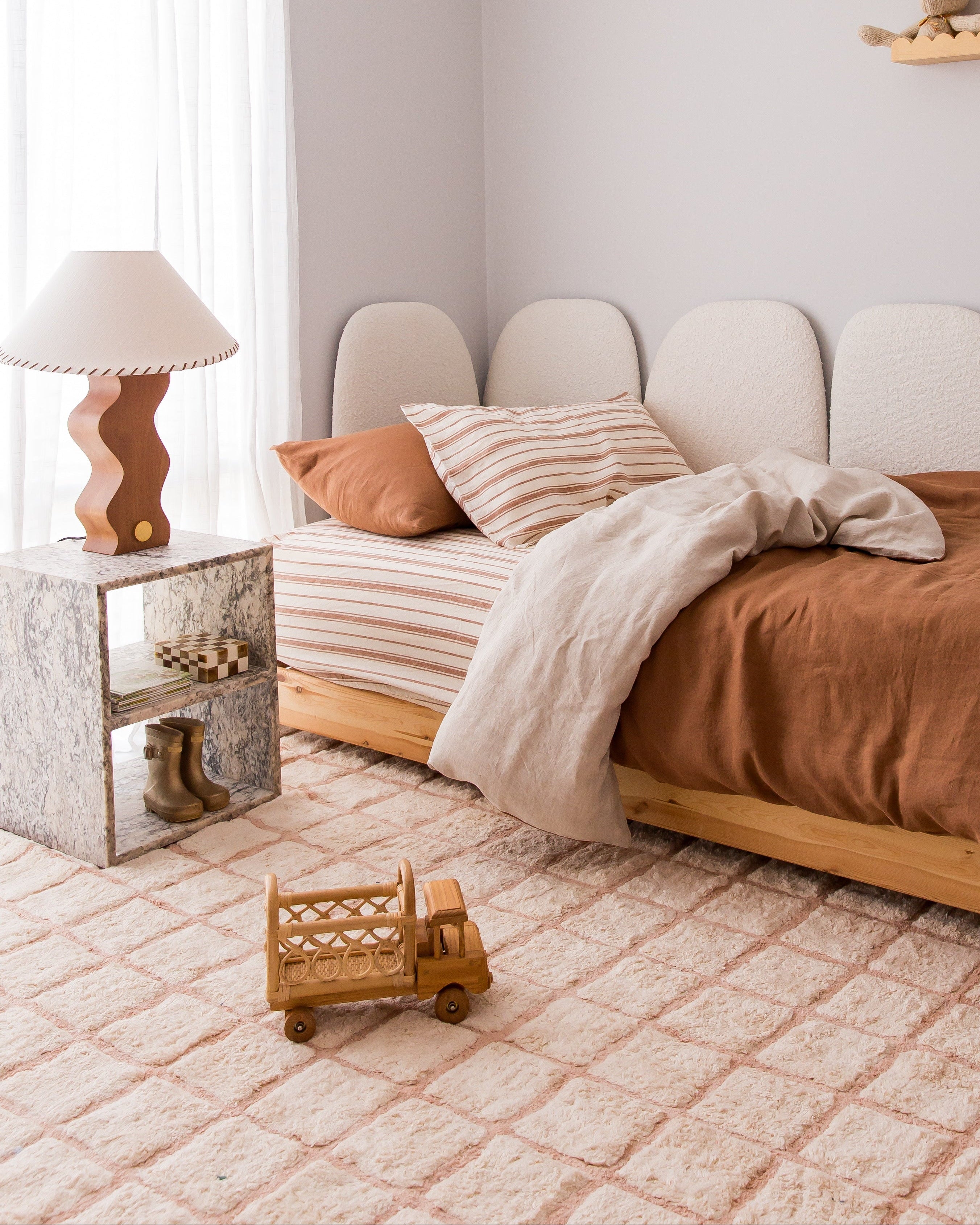 Neatly made bed with brown bedding in a bedroom setting.