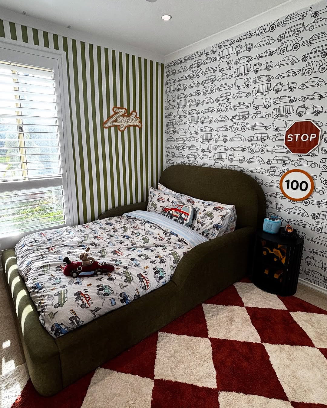 Children's bedroom with car-themed decor, including a bed with matching bedding and wall patterns.